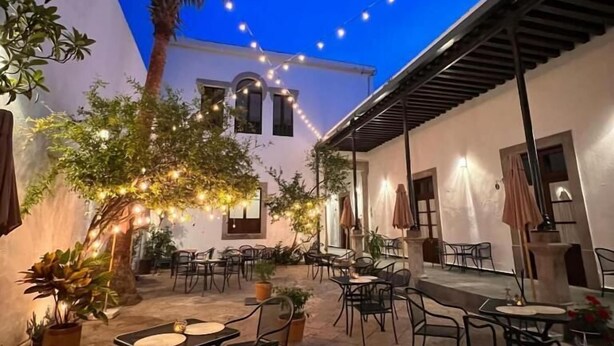 An outdoor patio area with tables and chairs, string lights, and potted plants. - La Casona de Josefa (Querétaro)