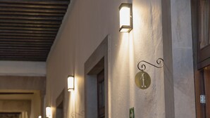 A corridor with wall-mounted light fixtures and numbered doors. - La Casona de Josefa (Querétaro)