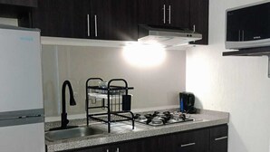A kitchen with dark wooden cabinets, a stainless steel sink, a gas stove, and a microwave. - RELAX AND QUIET PLACE (Q.R.)
