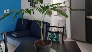 A modern kitchen with a built-in air conditioner, a dining table with chairs, a potted plant, and a refrigerator. - RELAX AND QUIET PLACE (Q.R.)