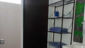 A bathroom with a toilet, a shelf with toiletries, and a shower area. - RELAX AND QUIET PLACE (Q.R.)