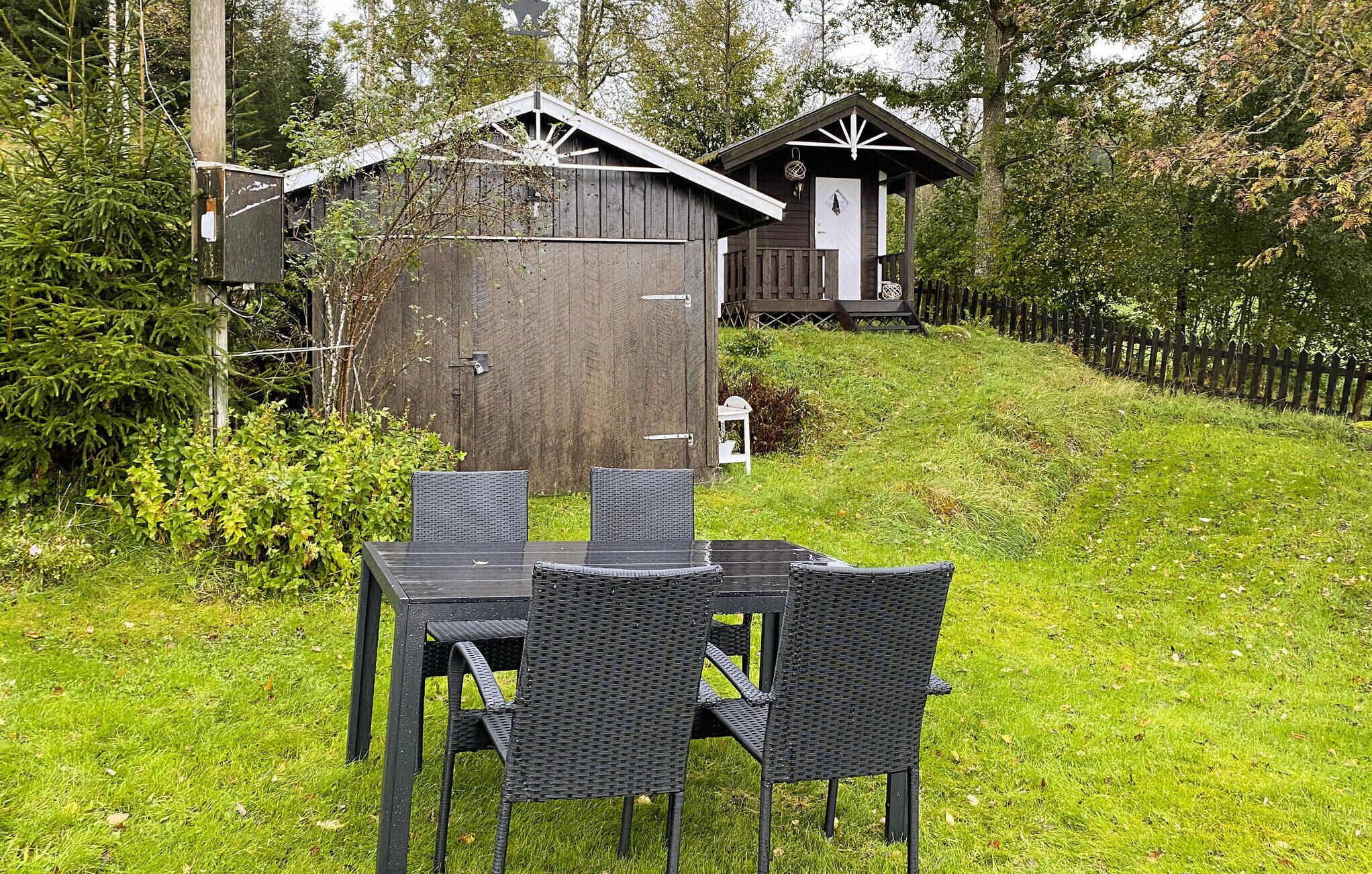 A rustic wooden cabin with a small porch and a dining area with a table and chairs.