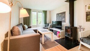 Una sala de estar acogedora con un sofá, un televisor, una chimenea y una ventana con cortinas.