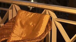 Un balcone con una sedia in vimini e vista su palme contro un cielo al crepuscolo.