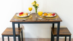 Una mesa de desayuno con platos de comida, vasos de jugo de naranja y un jarrón de rosas amarillas.