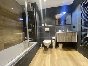 Une salle de bain moderne avec une douche à parois de verre, un meuble-lavabo en bois, des toilettes et un miroir.