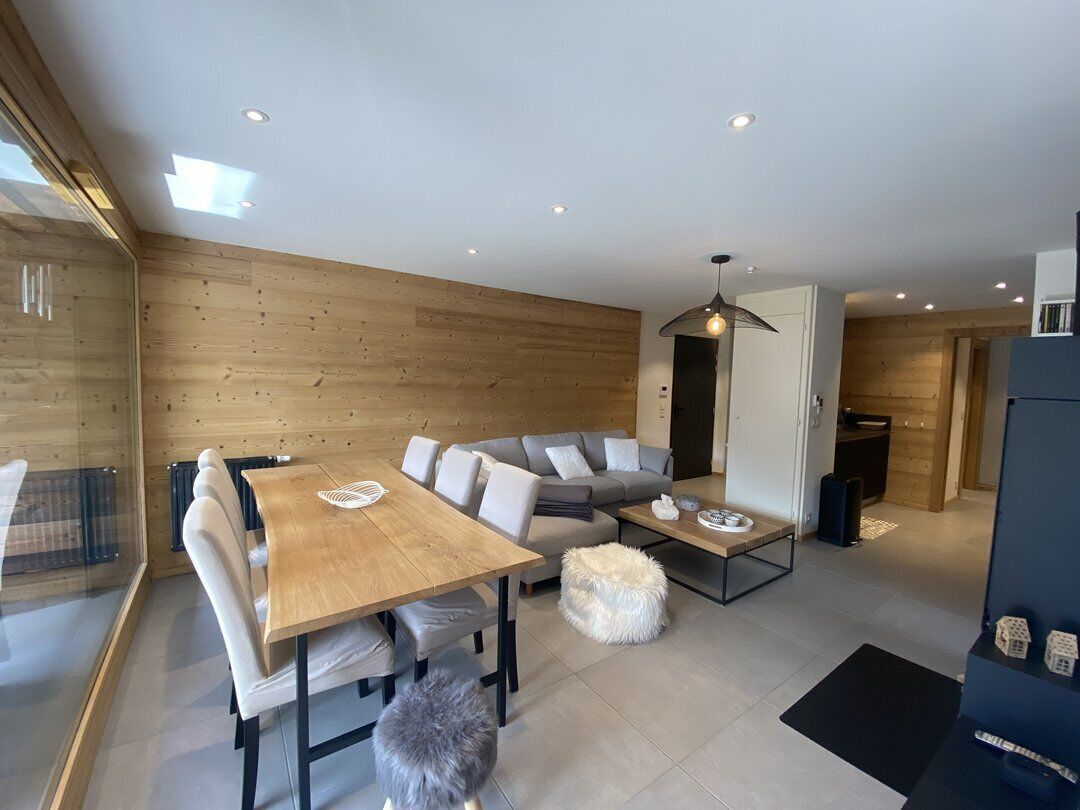 A modern living room with a wooden wall, a sofa, a dining table, and a coffee table.