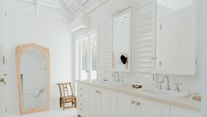 A spacious bathroom with white cabinetry, a large mirror, and a wooden chair. - White House (Byron Bay)