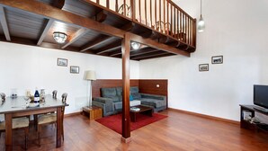 A spacious living area with a wooden staircase, a sofa, a dining table with chairs, and a television. - Chalet 'La Higuera' with Sea View, Shared Terrace and Wi-Fi (Frontera)