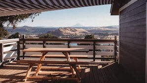 A wooden deck with picnic tables overlooking a mountainous landscape. - E+H House-Views! Fast Wifi & Pet friendly! (Lyle)
