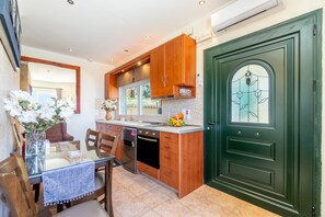 A kitchen with wooden cabinets, a glass table, and a green door.