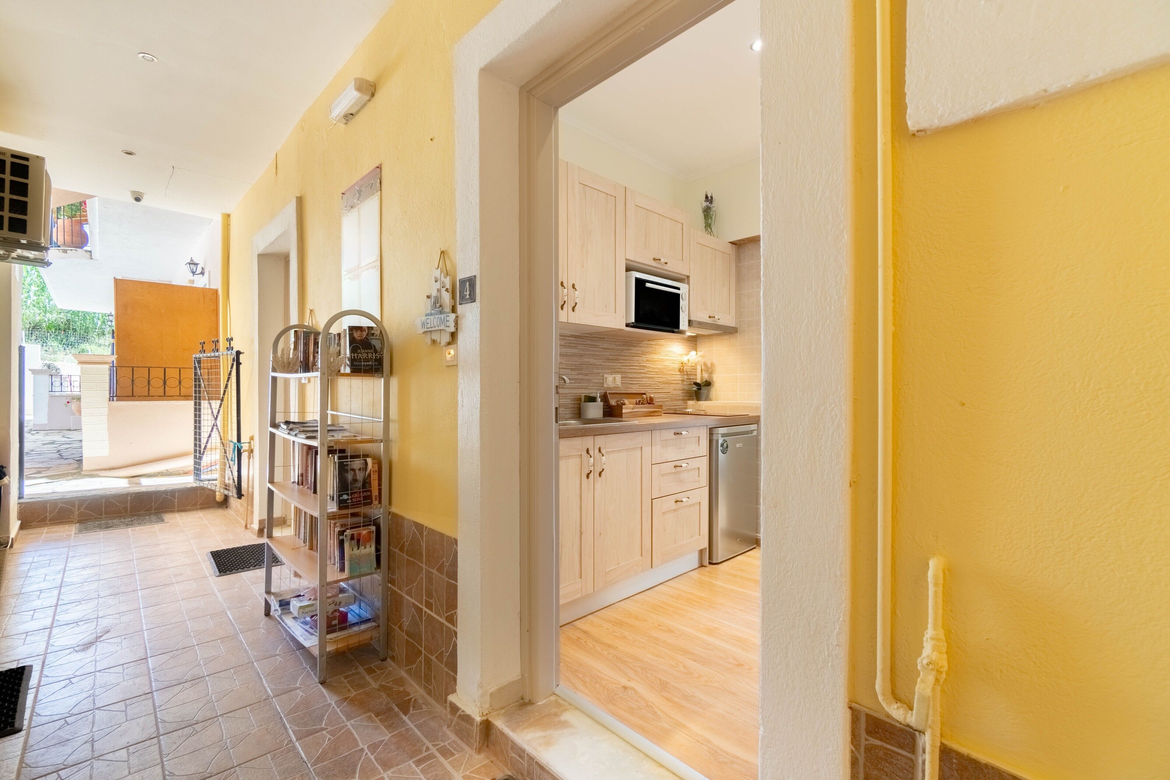 A hallway leading to a kitchen with wooden cabinets, a microwave, and a dishwasher.