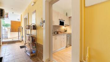 A hallway leading to a kitchen with wooden cabinets, a microwave, and a dishwasher.