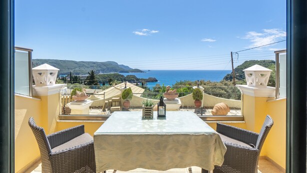 A balcony with a table, chairs, potted plants, and a view of the sea. - Studio Apartment "Angela 4" with Sea View, Shared Pool & Wi-Fi (Corfu)