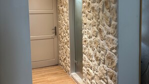 A hallway with a wooden floor, a stone wall, and a door. - Studio Apartment "Angela 4" with Sea View, Shared Pool & Wi-Fi (Corfu)
