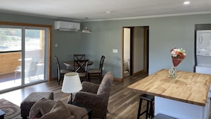 Eine moderne Küche mit Holzarbeitsplatte, ein Essbereich mit Tisch und Stühlen sowie ein Wohnbereich mit Sofa und Lampe.