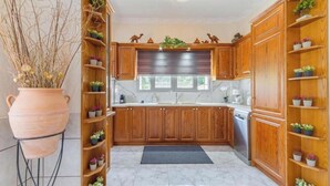 Una cocina con armarios de madera, encimera de mármol y un jarrón grande con plantas.