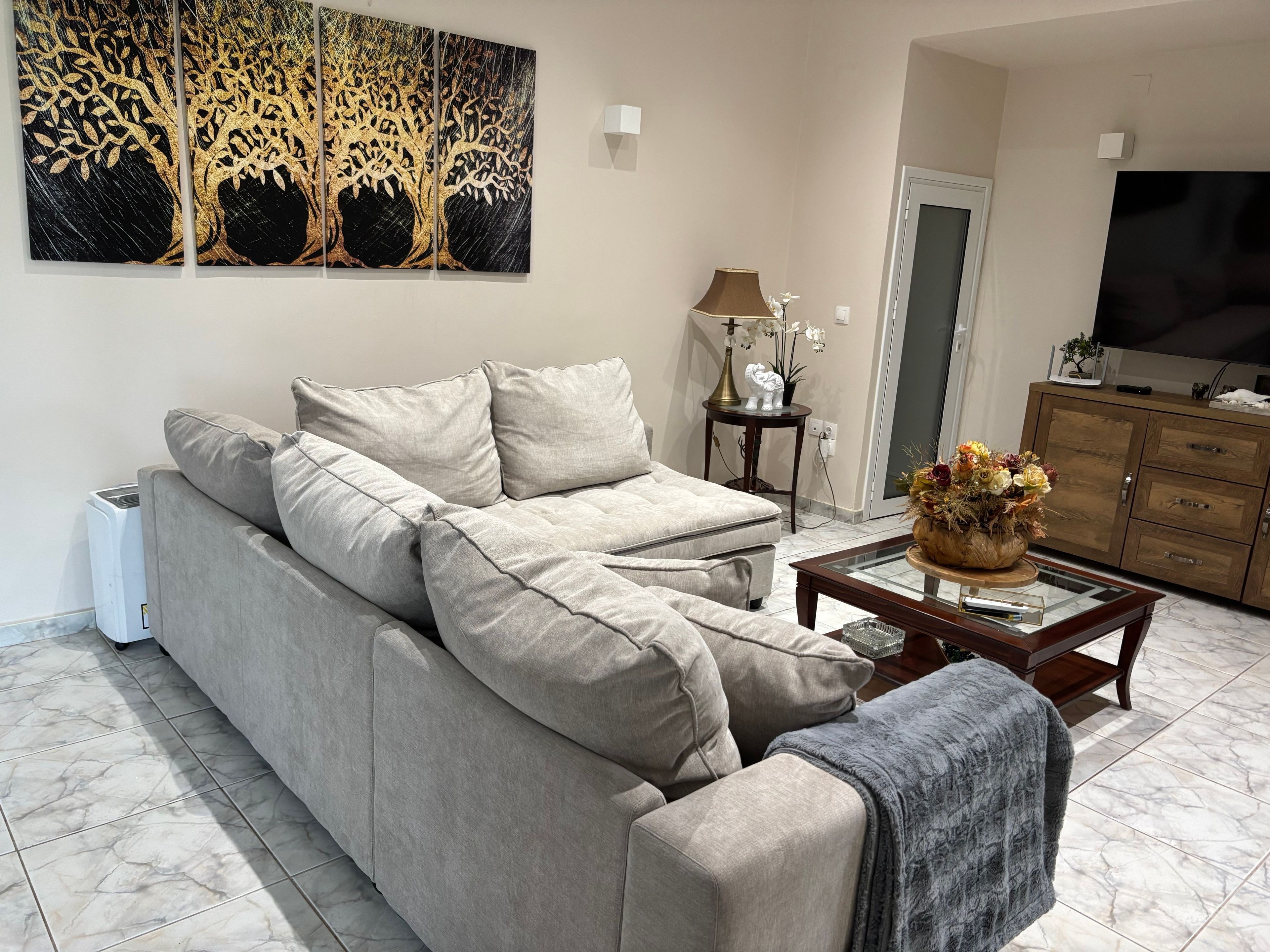 Una sala de estar con sofá, mesa de centro, televisor y un cuadro en la pared.