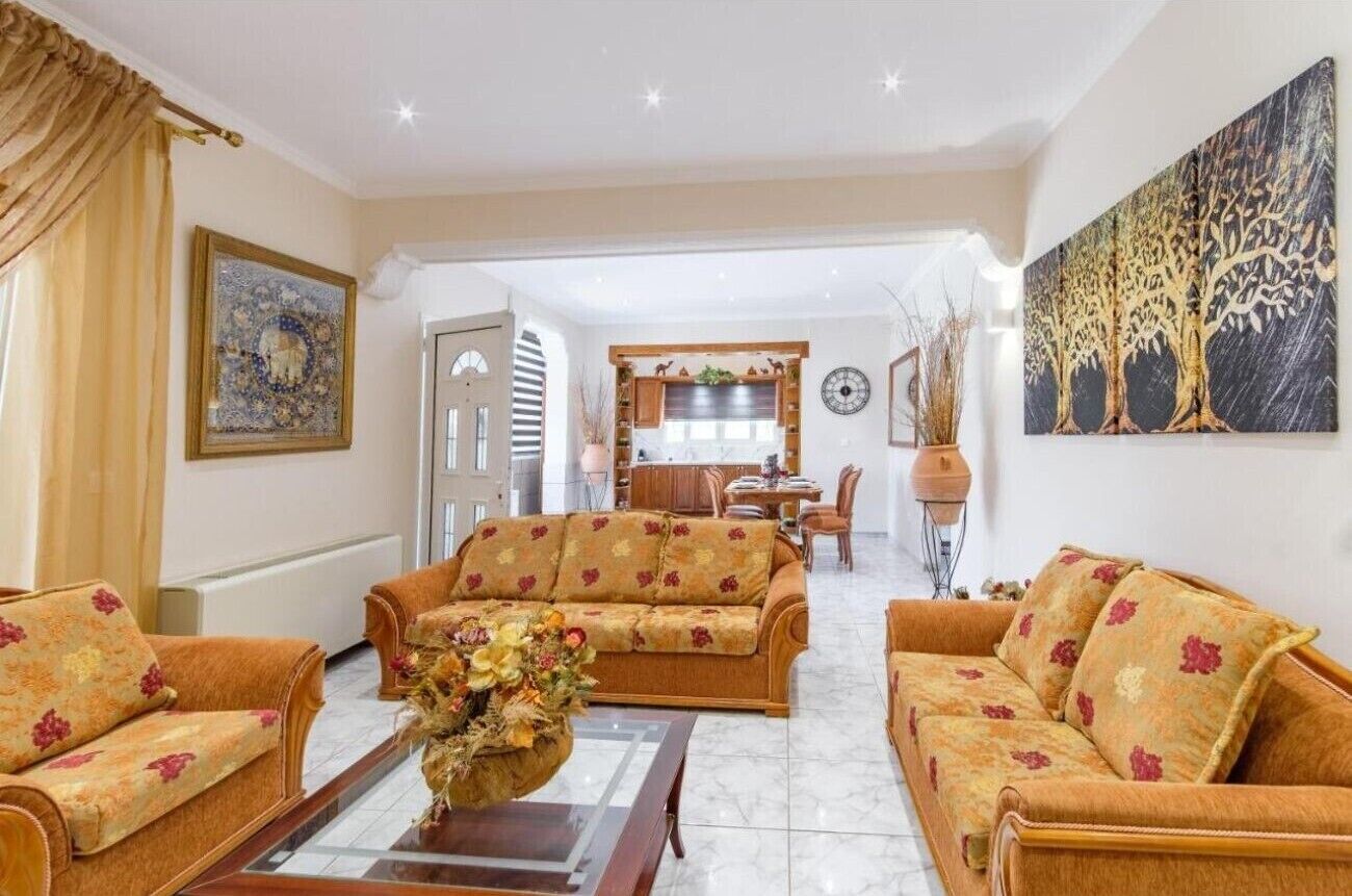 A living room with sofas, a coffee table, and a dining area in the background.