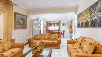 A living room with sofas, a coffee table, and a dining area in the background.
