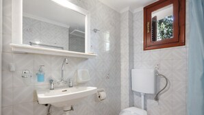 Een badkamer met een wastafel, spiegel, toilet en raam.