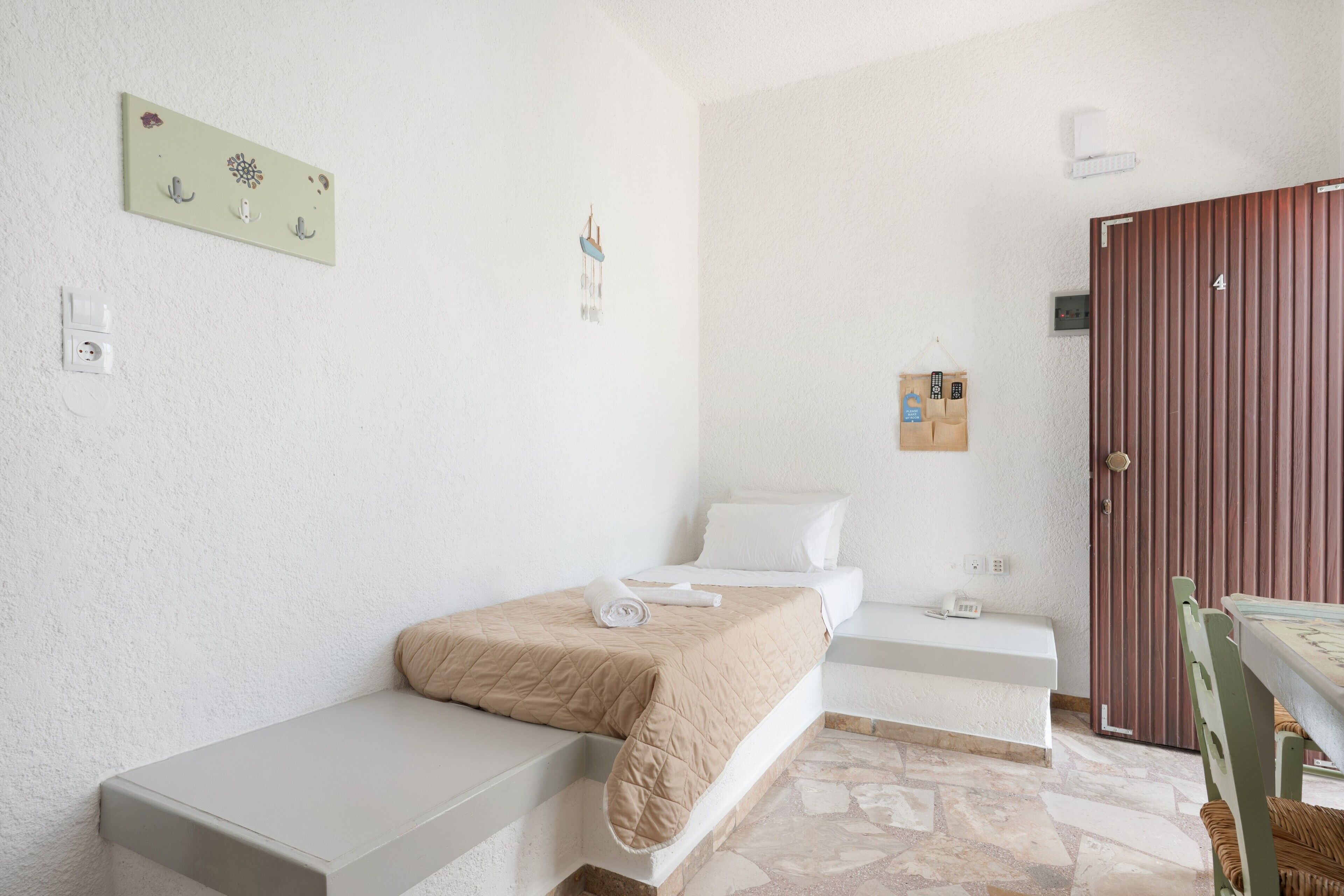 Ein Schlafzimmer mit einem Bett, einer Bank, einem kleinen Tisch und einer Tür.