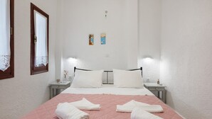 Een slaapkamer met een bed, twee nachtkastjes, een raam met gordijnen en wanddecoratie.