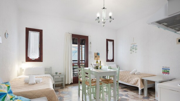 A room with a bed, a desk, a chair, a table, and a hanging light fixture.