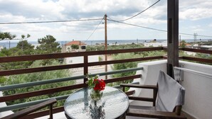 A balcony with a glass table, a wooden chair, and a vase with flowers.