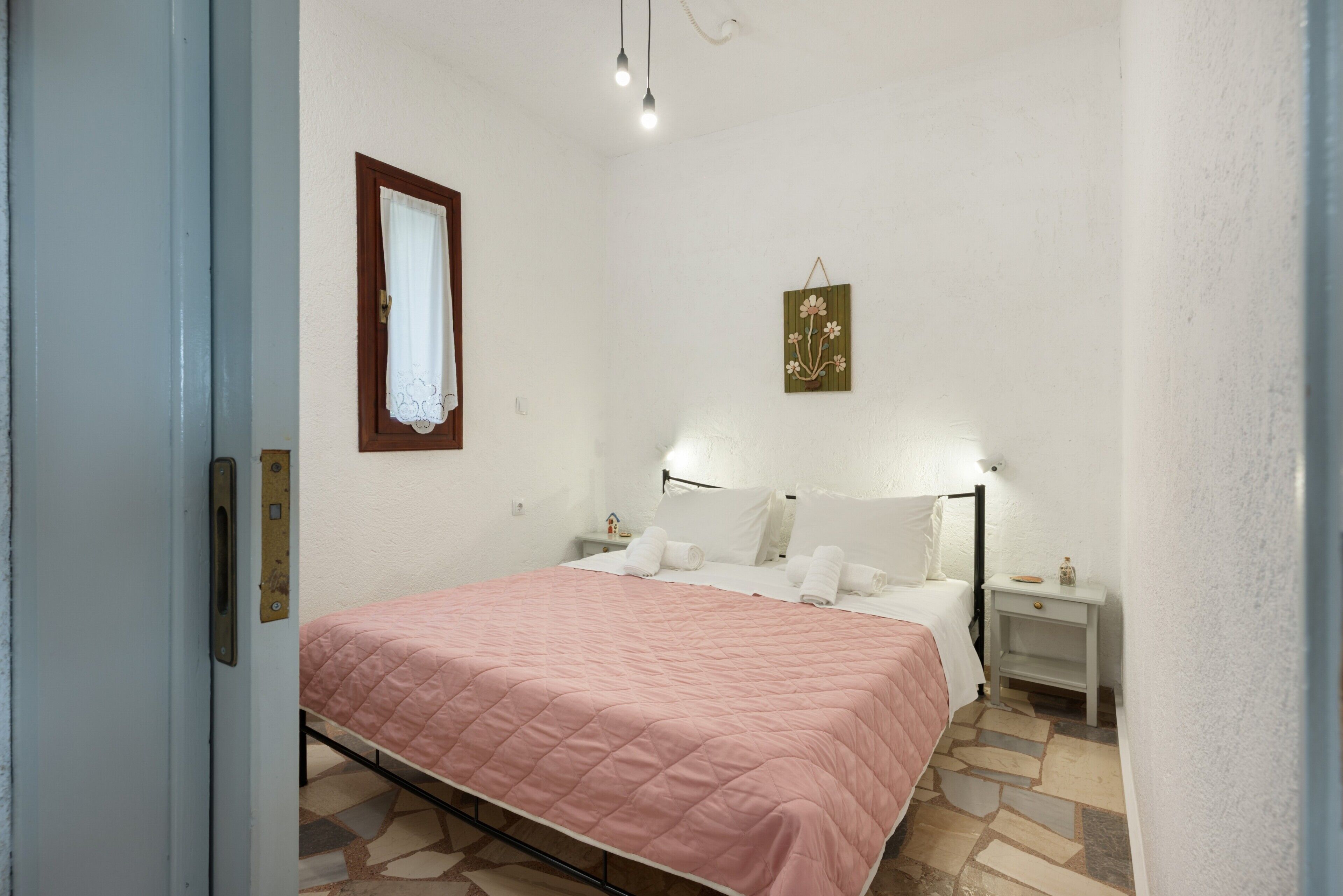 Un dormitorio con cama, mesitas de noche, lámpara de pared y un adorno.