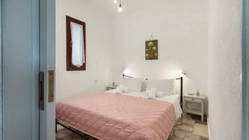 Un dormitorio con cama, mesitas de noche, lámpara de pared y un adorno.
