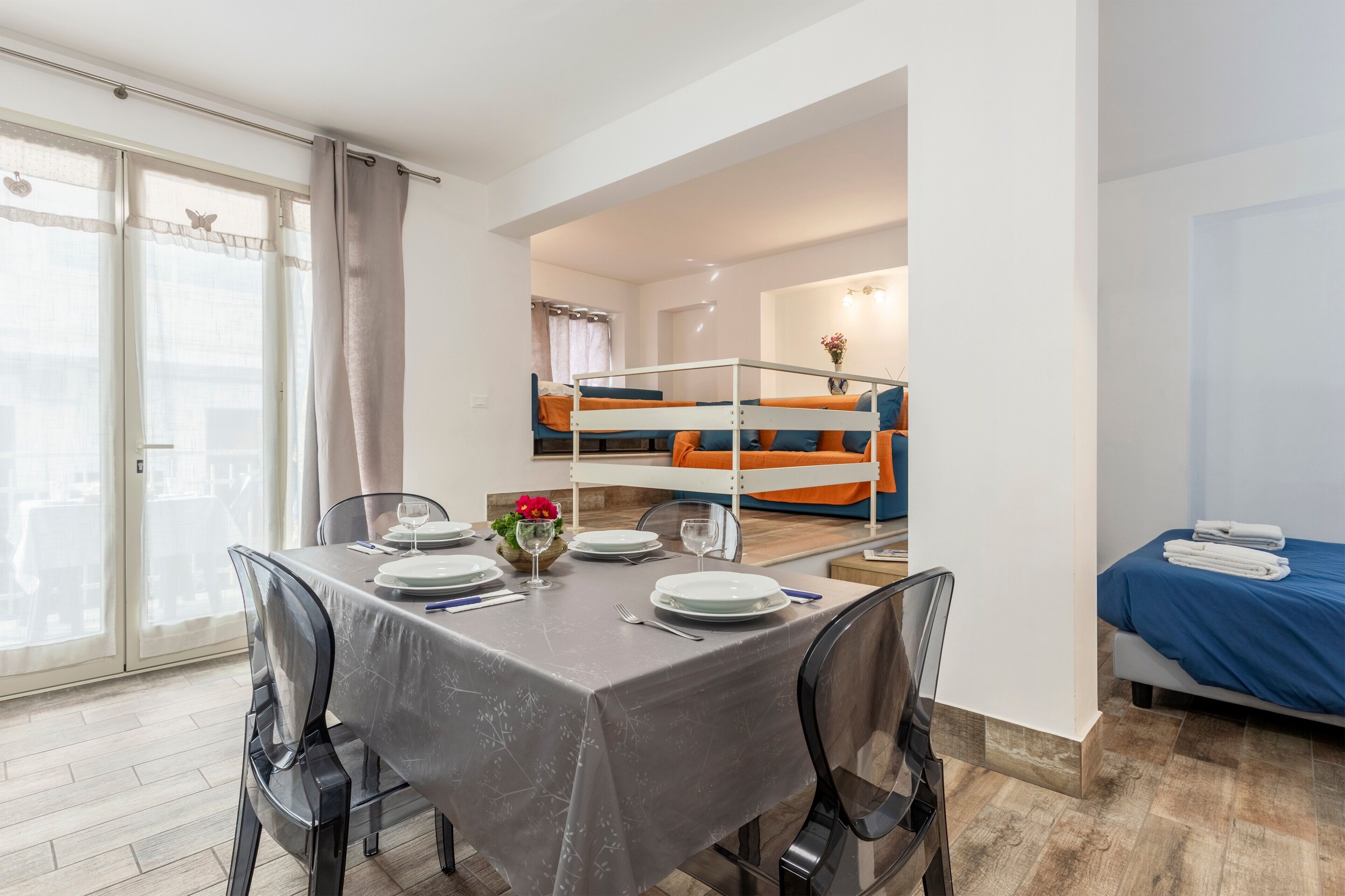Ein Zimmer mit Esstisch für vier Personen, einem Stockbett und einem Bett mit blauer Bettdecke.