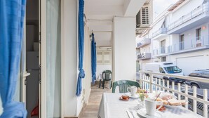 A balcony with a table set for breakfast, a view of the street, and a building with balconies.