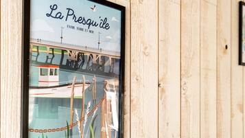 Un cuadro con un puente, el texto 'La Presqu'ile ENTRE TERRE ET MER' y un pájaro.