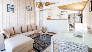 Una sala de estar con sofá, una mesa de vidrio, alfombra estampada y paredes de madera.