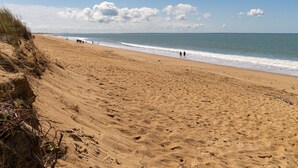Une plage avec du sable, des vagues et un ciel dégagé.