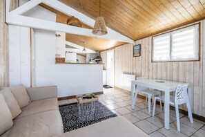 En modern inredning med en soffa, ett matbord och stolar, ett träpanelat tak och ett köksområde.