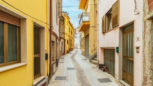 A narrow street with buildings on either side, a cobblestone path, and closed shutters on the windows. - Vacation Home "Jerzu Centro 2" with Private Terrace & Balcony (Jerzu)