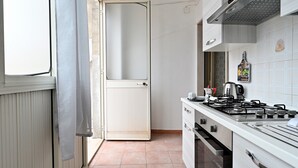 A kitchen with a stove, oven, and a door leading to another room. - Vacation Home "Jerzu Centro 2" with Private Terrace & Balcony (Jerzu)