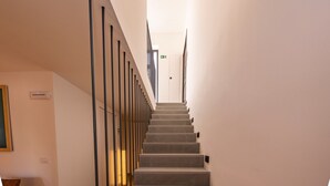 Una escalera con barandilla, una puerta arriba y un accesorio de luz en la pared.