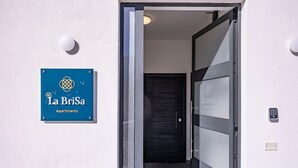 Un letrero azul con 'La BriSa Apartments' y una puerta moderna con teclado numérico.