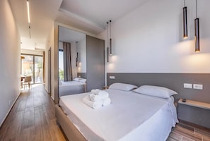 A modern hotel room with a large bed, a bedside table, a chair, and a view through the glass door.