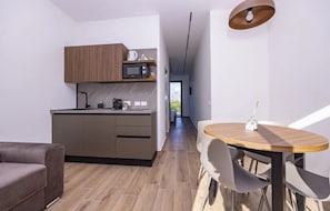 A modern kitchen with a microwave, kettle, and coffee maker, a dining area with a round table and chairs, and a sofa. - Holiday Apartment "La Brisa - Maestrale' with Mountain View, Private Terrace & Wi-Fi (Capo d'orlando)