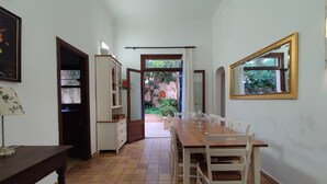 Un comedor con mesa y sillas de madera, una lámpara y vistas a un jardín a través de una puerta abierta.