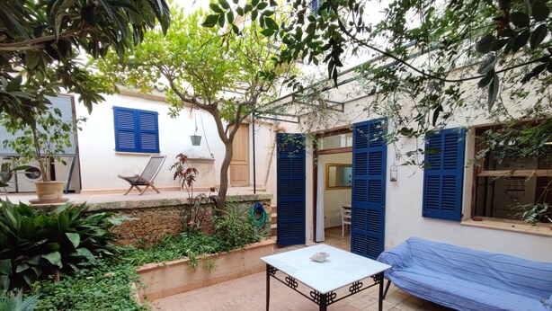 Un patio con una mesa, un banco y una zona cubierta.