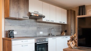 Une cuisine moderne avec des meubles en bois, un four encastré et un grand téléviseur à écran plat.