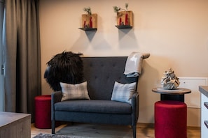 A modern living room with a grey sofa, red ottomans, and wall-mounted shelves with decorative items.