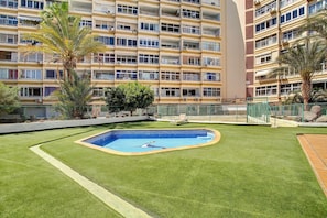 Edifício residencial com várias varandas, piscina e áreas verdes ao redor.