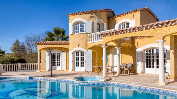 Blick auf einen Pool vor einem Haus im mediterranen Stil, mit Swimmingpool, weißen Fensterläden und einem Ziegeldach.