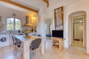 A kitchen with a dining area, a washing machine, a TV, and a large mirror.